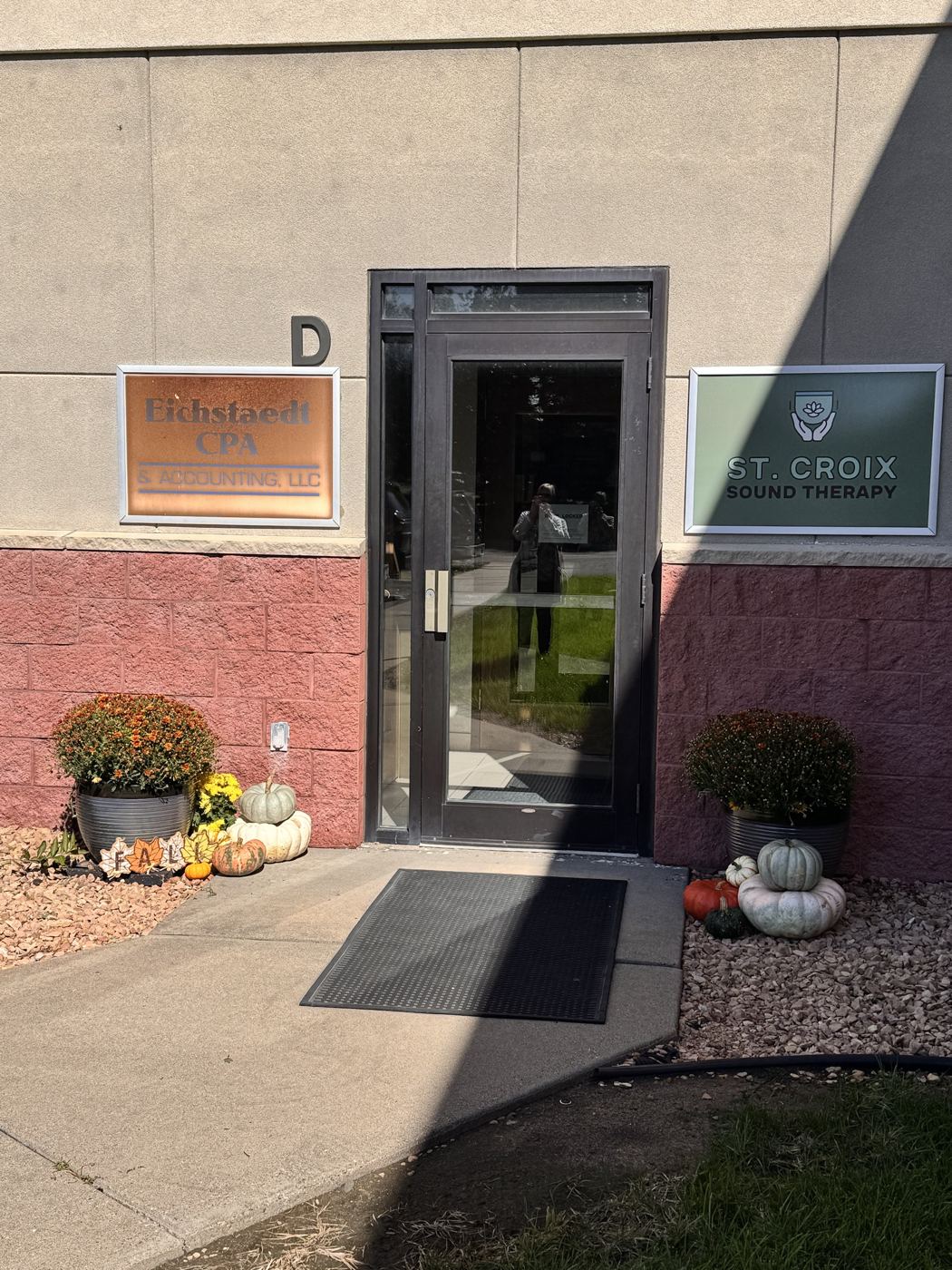Office entrance with potted mums and stacked white pumpkins