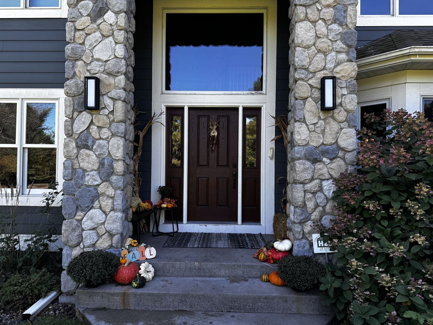 Stone-column entry with corn stalks, mums and pumpkins on the steps